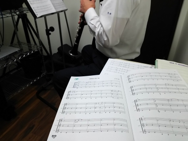 楽譜に囲まれクラリネットを演奏する生徒