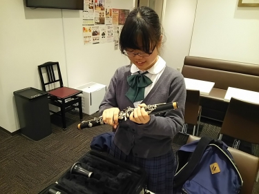笑顔でクラリネットを片付ける生徒