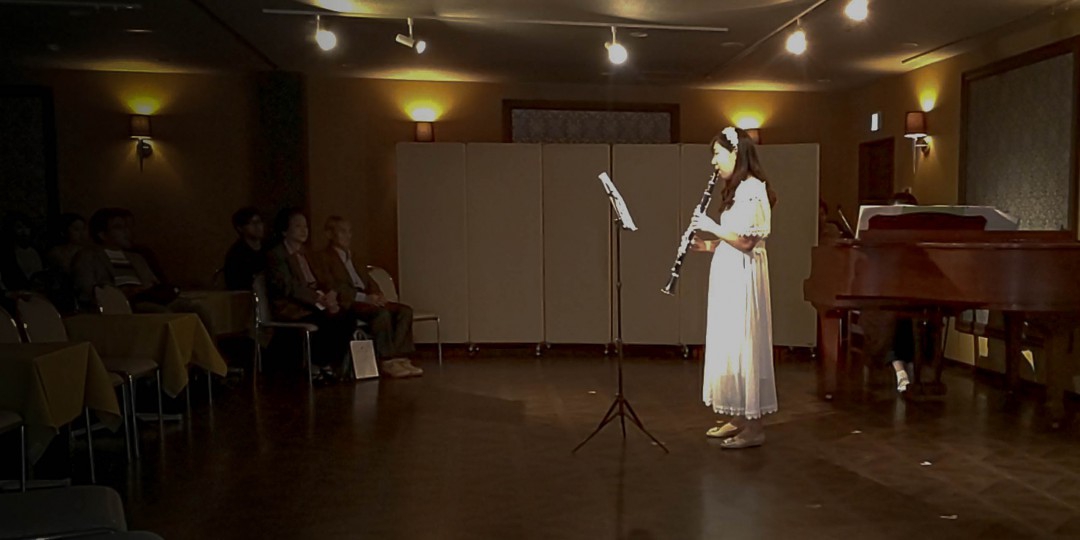 発表会のステージでライトを浴びて演奏するクラリネット奏者