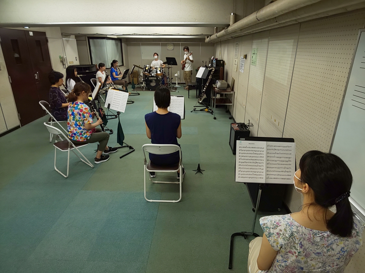 バンドアンサンブルで楽しく演奏するメンバーと見学者