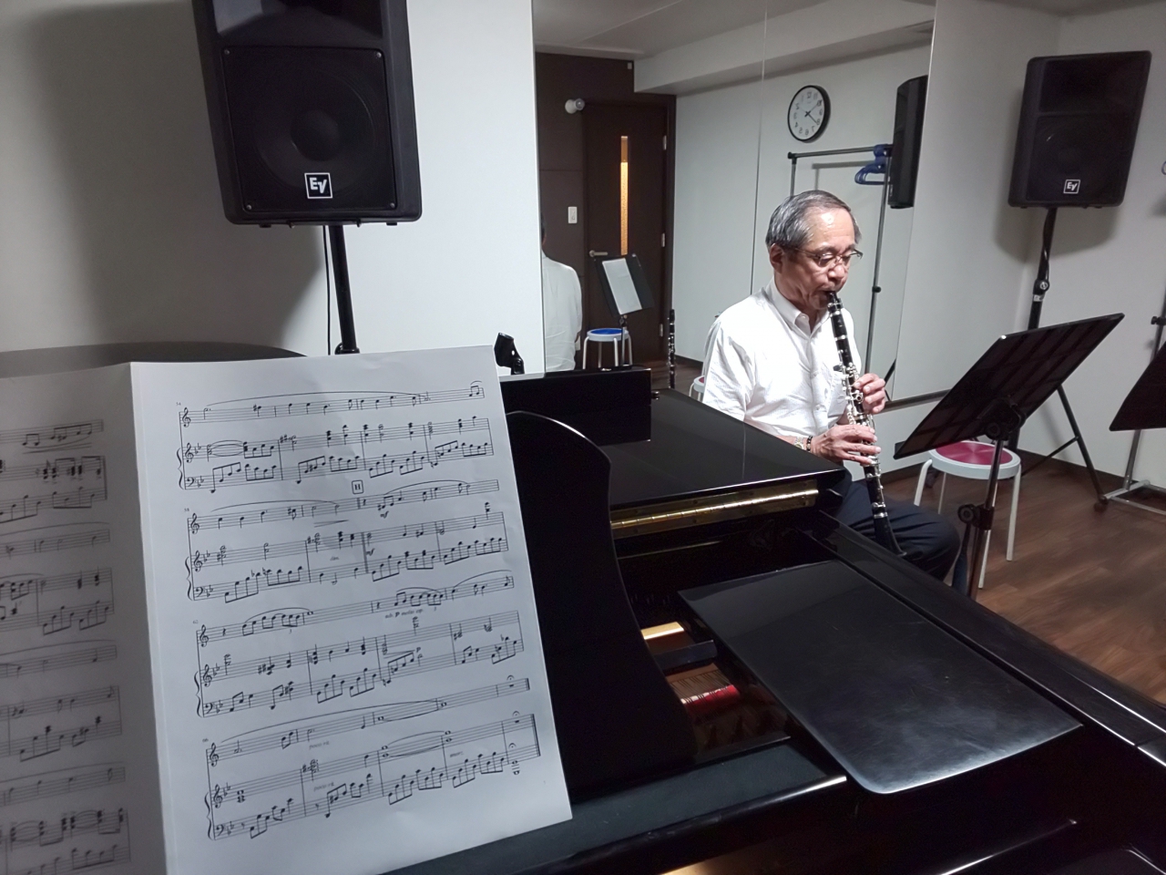 座って演奏する生徒とグランドピアノ